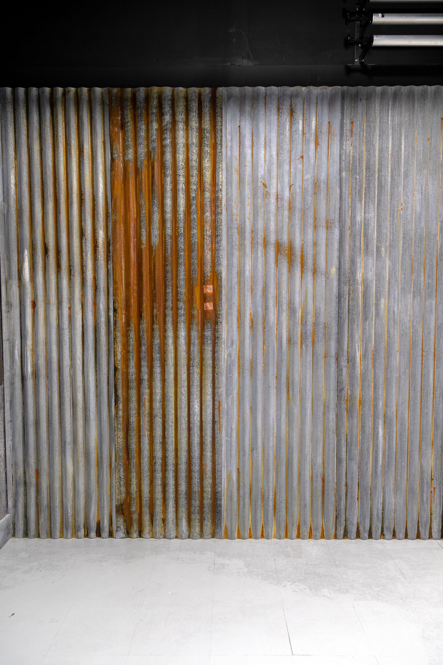 Rustic corrugated metal sheet backdrop wall with rust patina details in a photography studio setting.