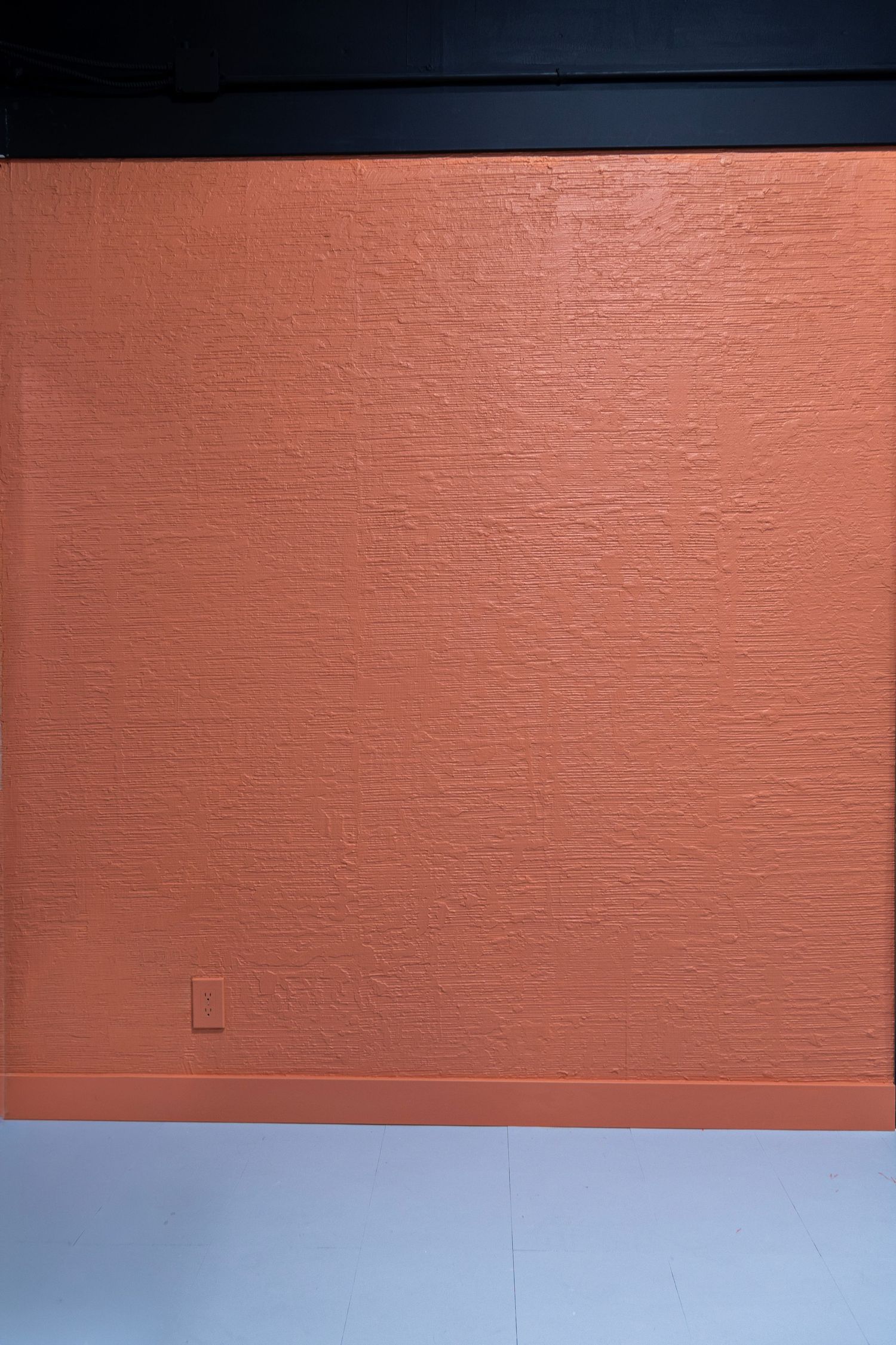Textured terracotta orange painted concrete backdrop wall in a professional photography studio space.