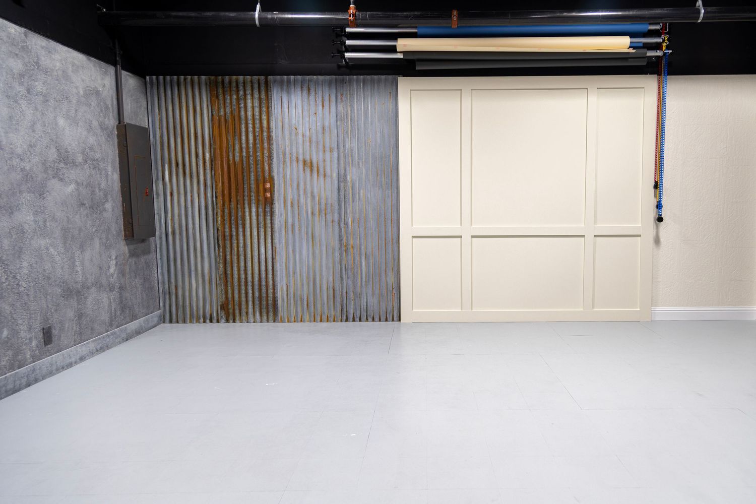 Photography studio backdrop wall with corrugated metal, concrete texture, and white paneling.