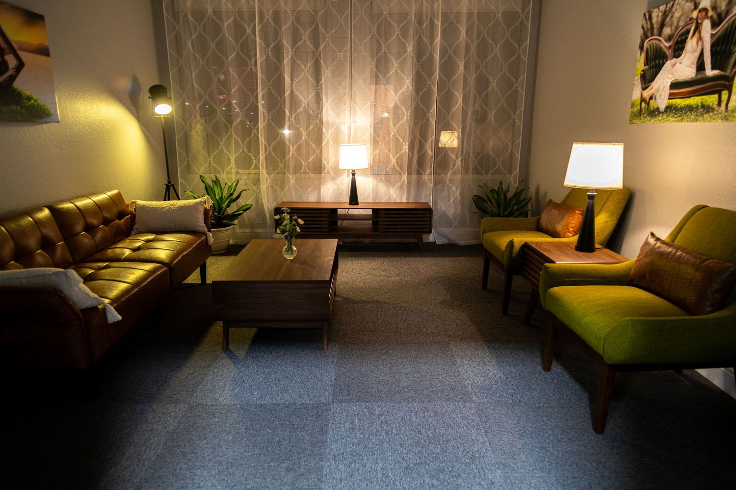 Cozy mid-century modern living room set with warm lighting, leather sofas, and green chairs.