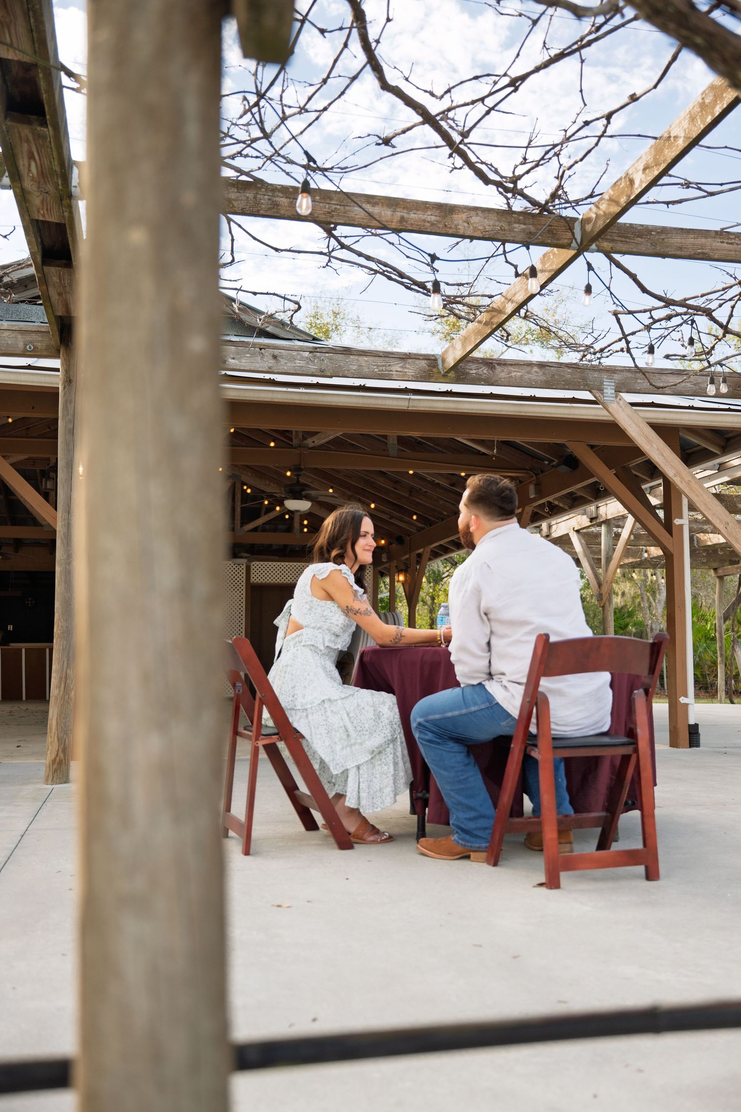 A group of people relax in wooden Adirondack chairs on a covered outdoor patio.