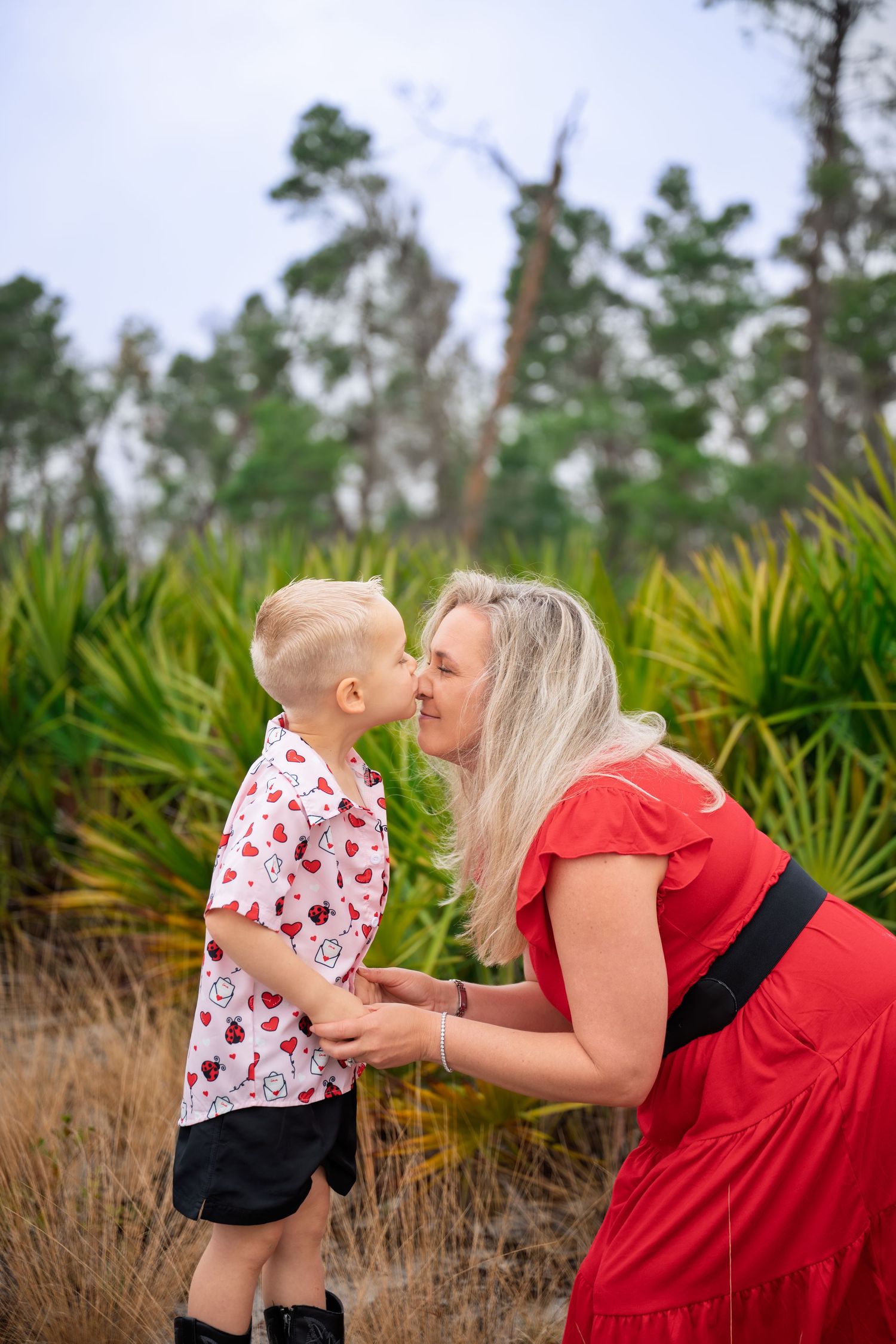 A tender moment captured in a natural setting with palm trees and grass in the background.