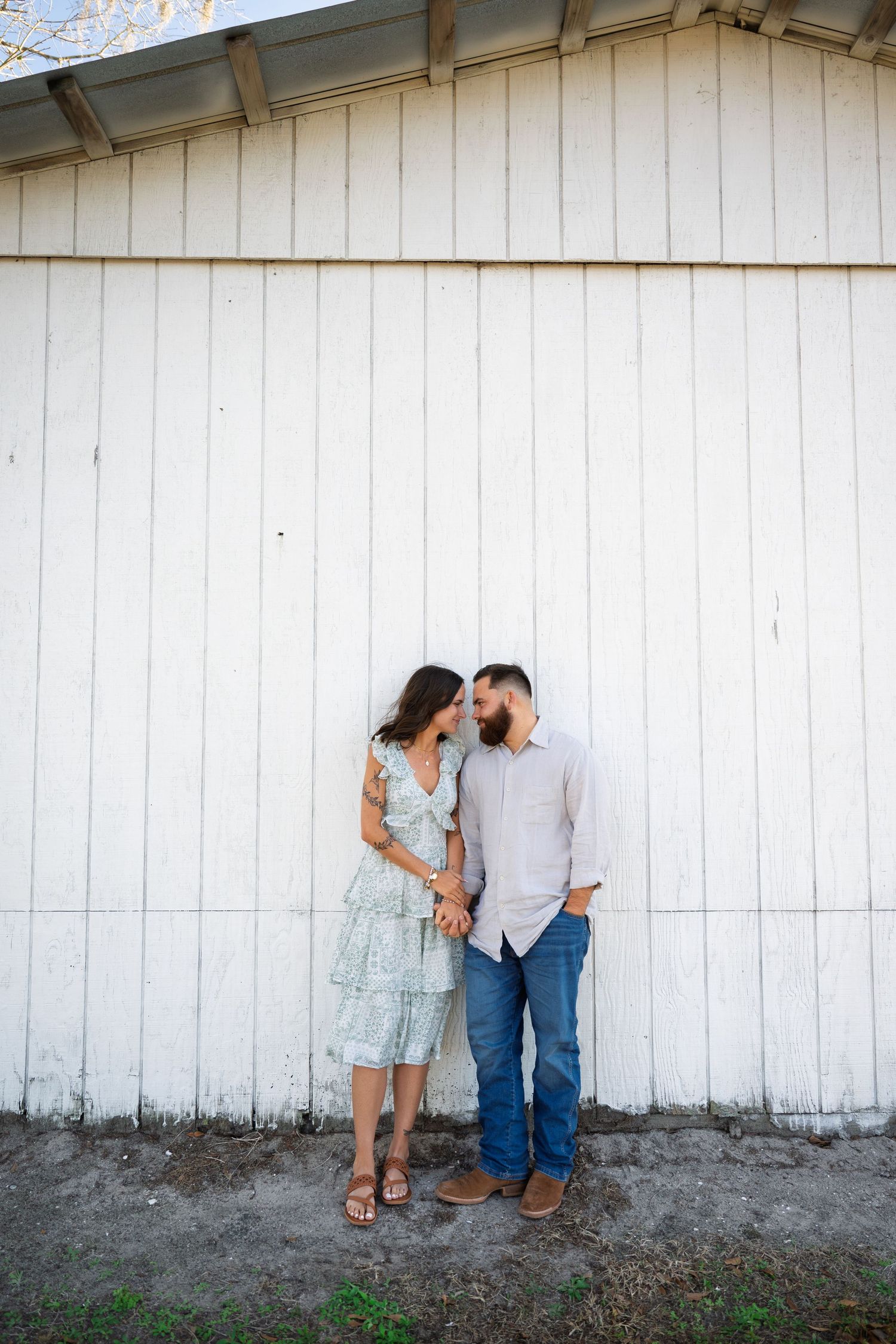 A couple shares a romantic moment against a rustic white wooden wall in a series of three connected photos.