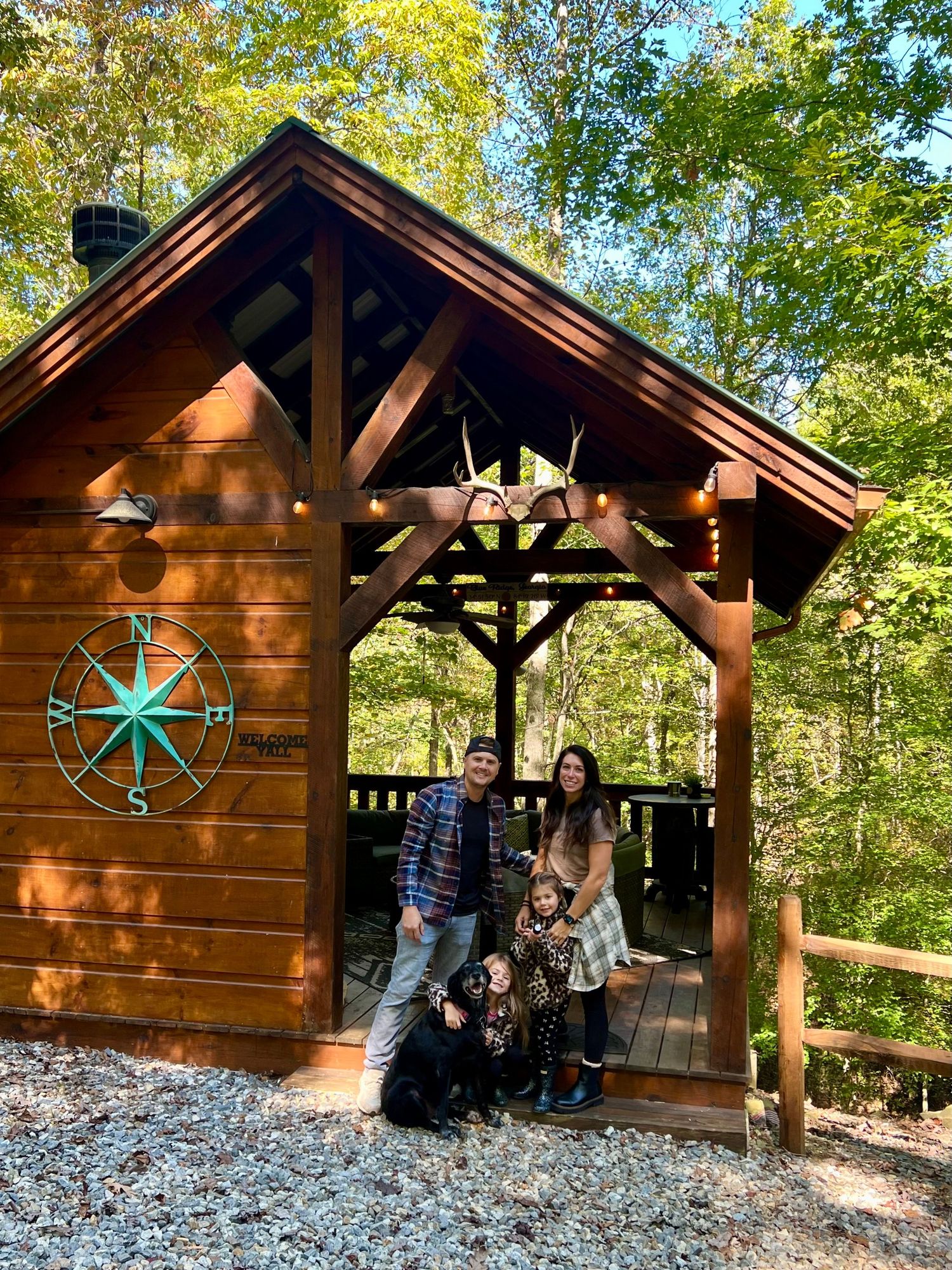 A rustic wooden cabin with decorative windmills sits nestled among autumn trees.