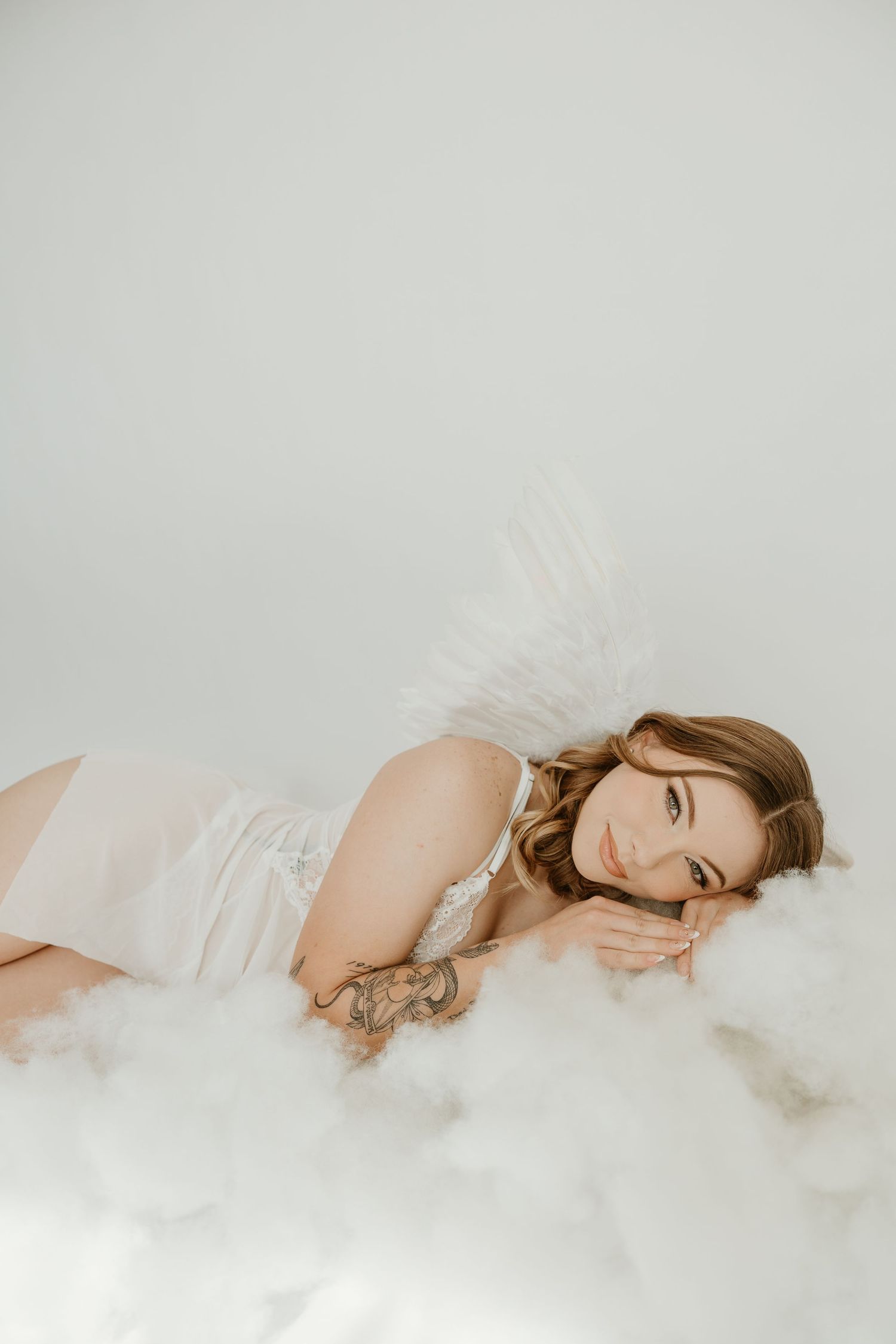 Nashville boudoir photography featuring angel wings, white lingerie, and a dreamy cloud set.