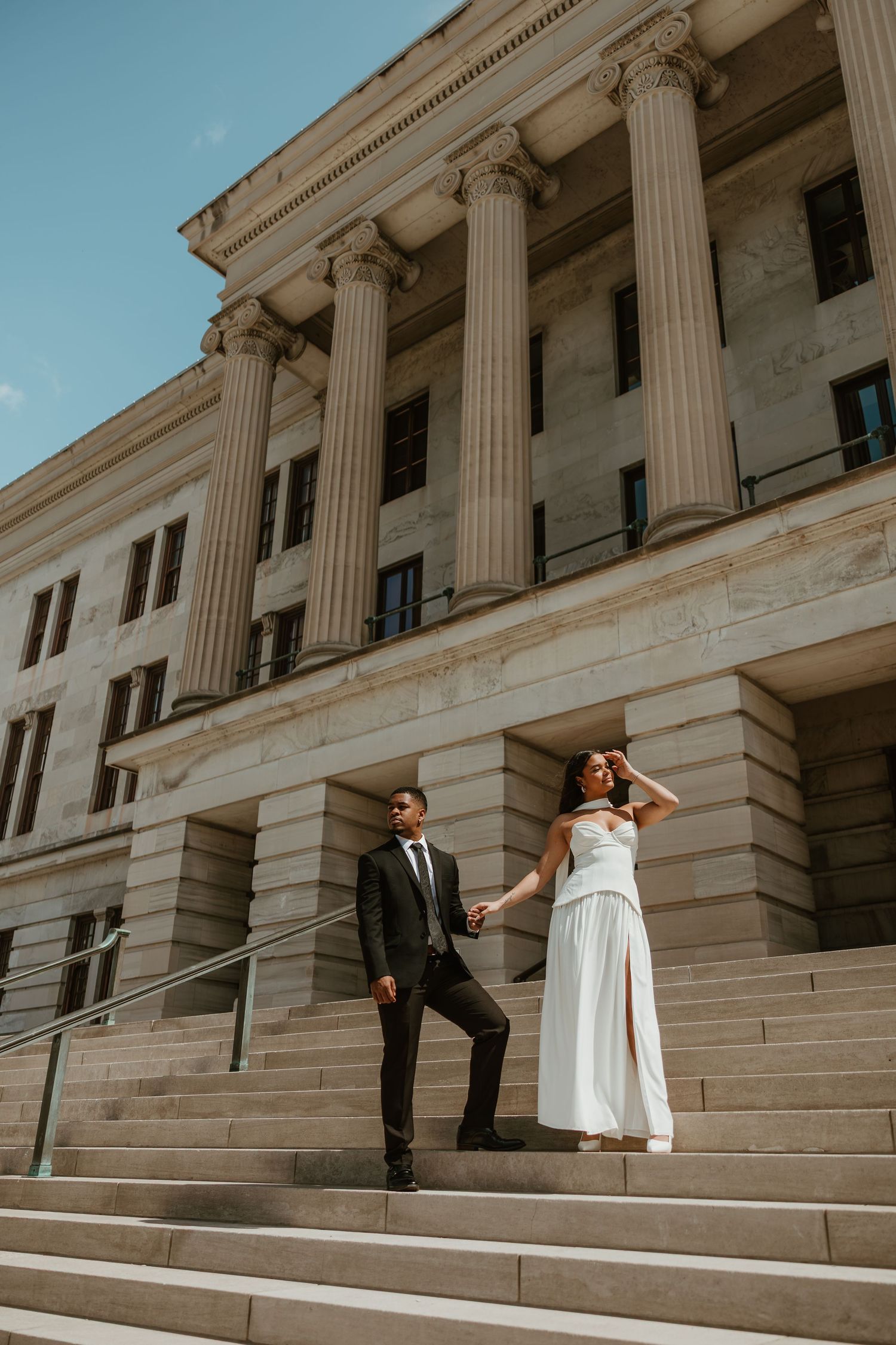 Nashville area engagement session with a couple standing outside luxury column building in golden sun warm true tone color edit