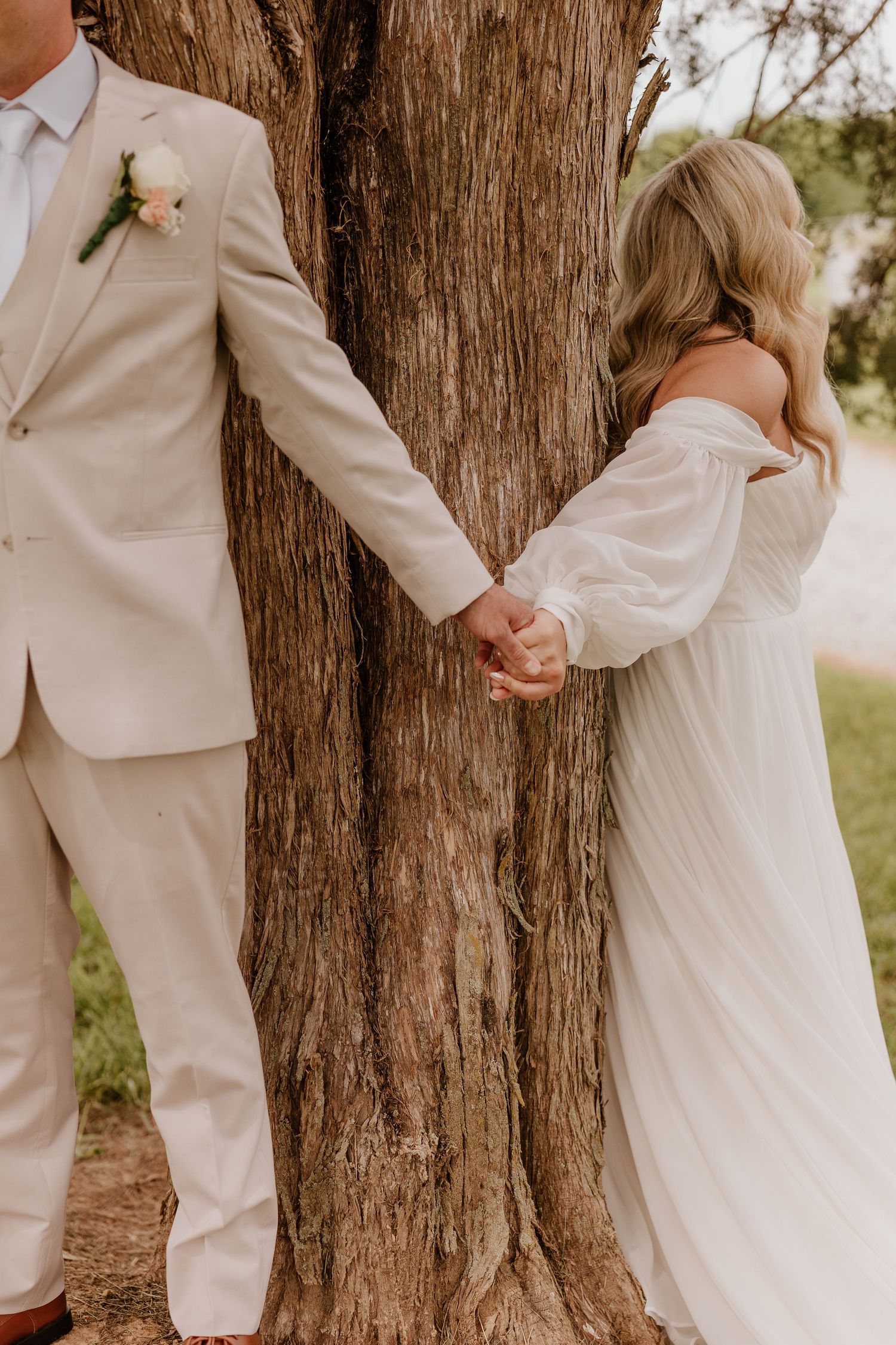 Bride and groom holding hands before their first look, sharing a romantic wedding moment beneath a tree in Tennessee.