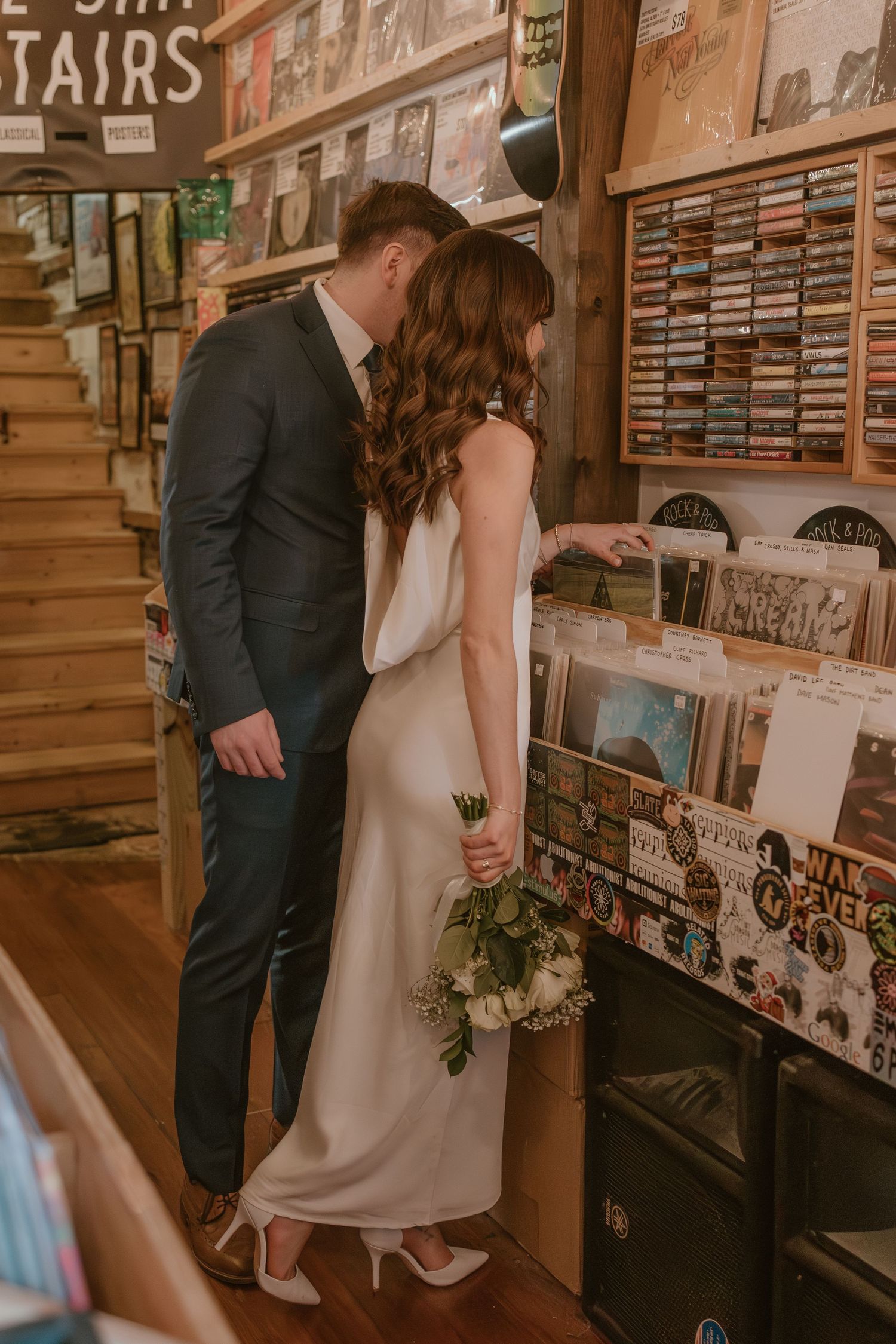 Bride and groom browsing vinyl records in a record store during a fun and unique wedding portrait session. Elopement downtown clarksville