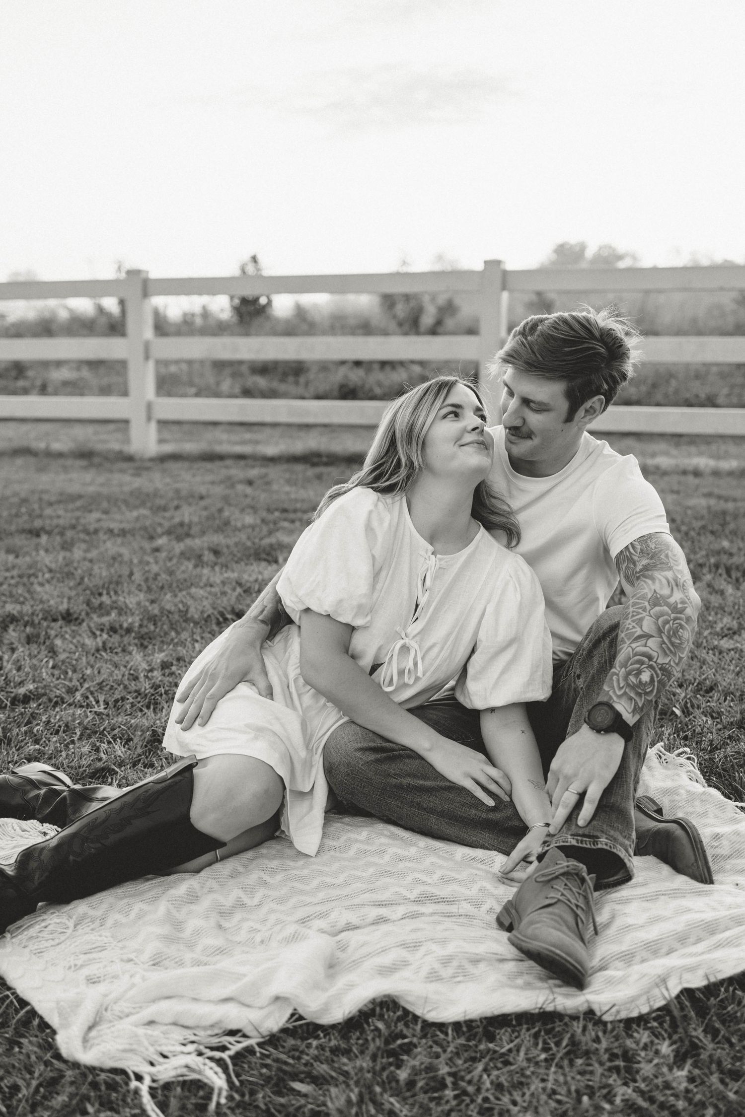 Black and white maternity announcement portrait of an expecting couple cuddling on a blanket at the park in Clarksville, TN.