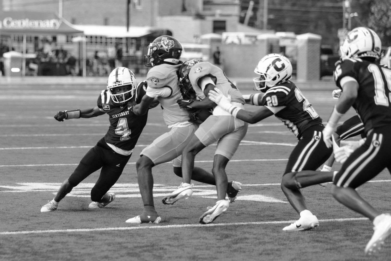 Black and white action shot of football players tackling during competitive college football game.