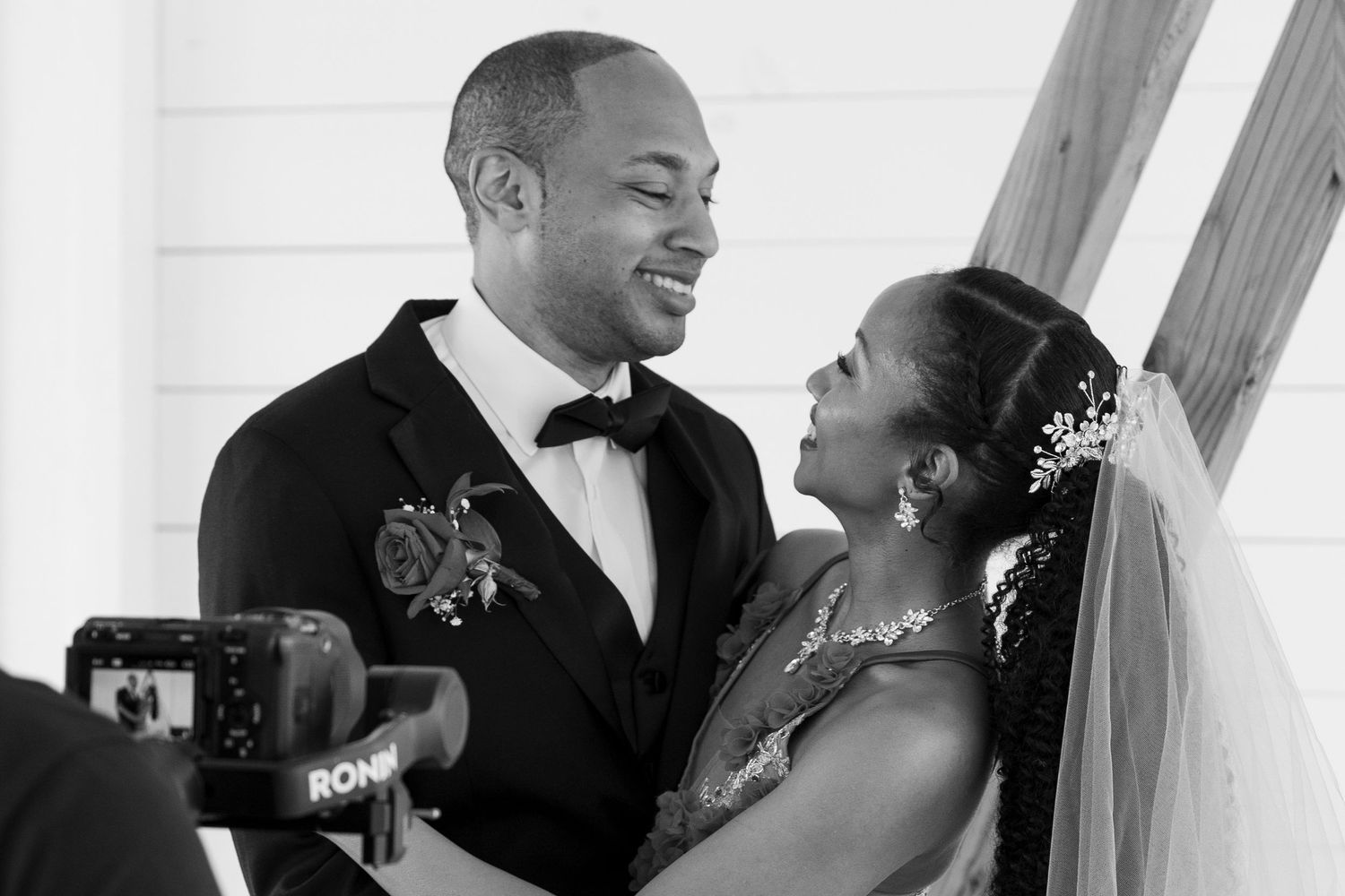 A black and white photo of a smiling bride and groom sharing a joyful moment at the altar.