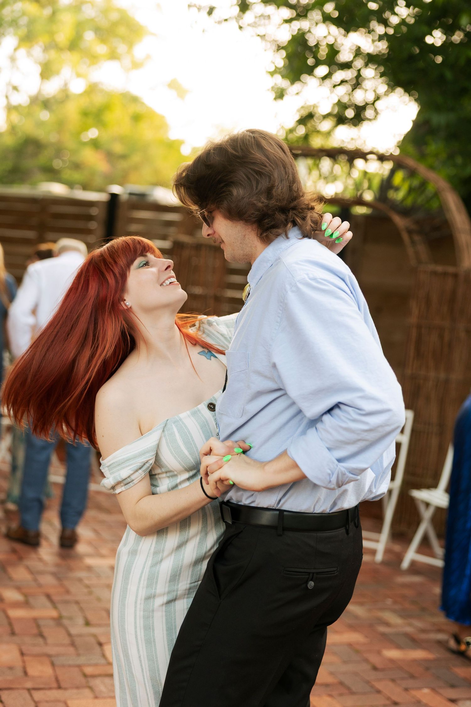 Couple dancing closely and laughing together at an outdoor wedding reception.