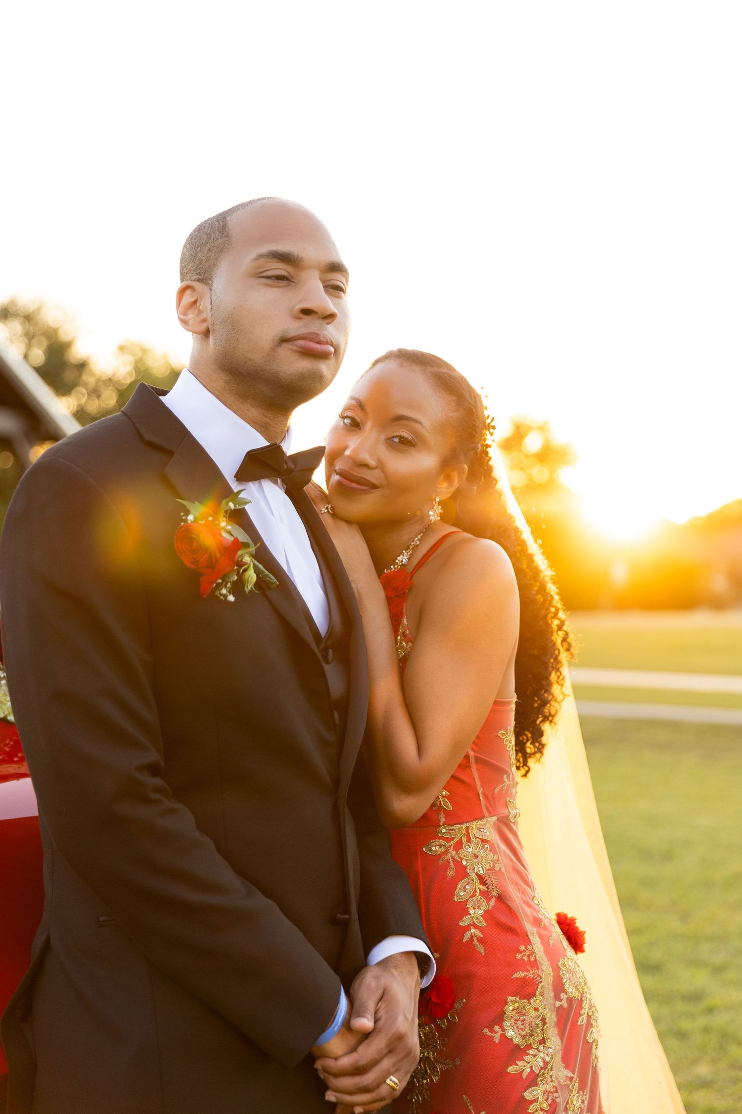 Elegant couple in formal wedding attire holding hands during a stunning golden sunset outdoor portrait session.
