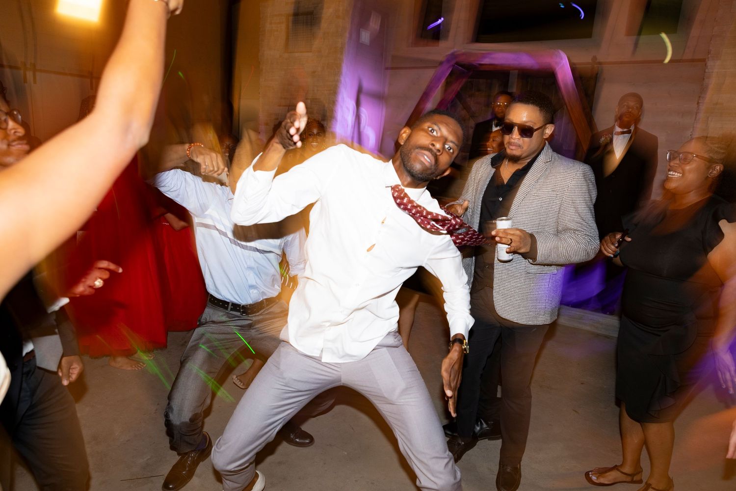 A wedding guest energetically dancing at an outdoor wedding reception celebration.