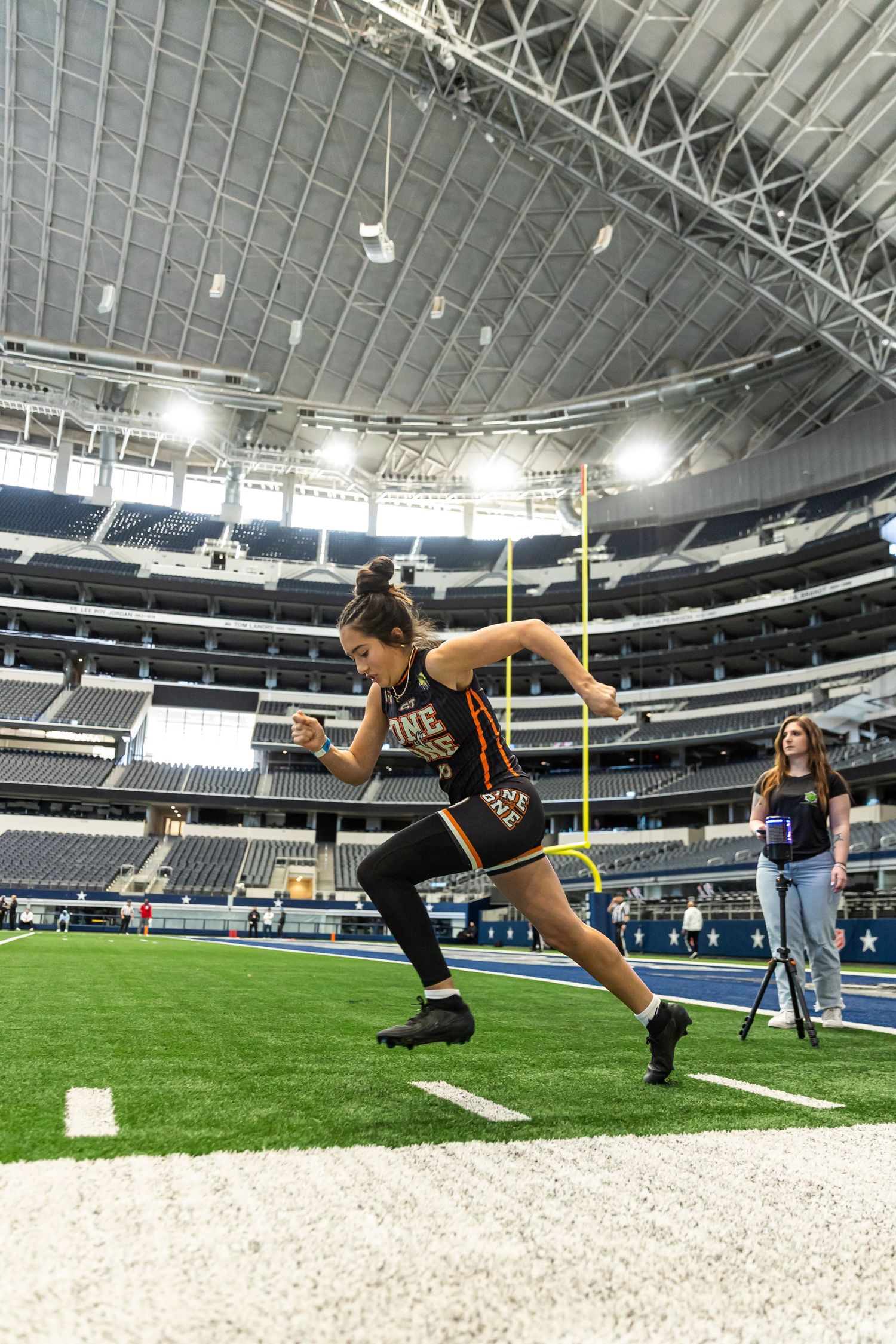Female athlete sprints during a football combine drill inside AT&T Stadium in Arlington, Texas.