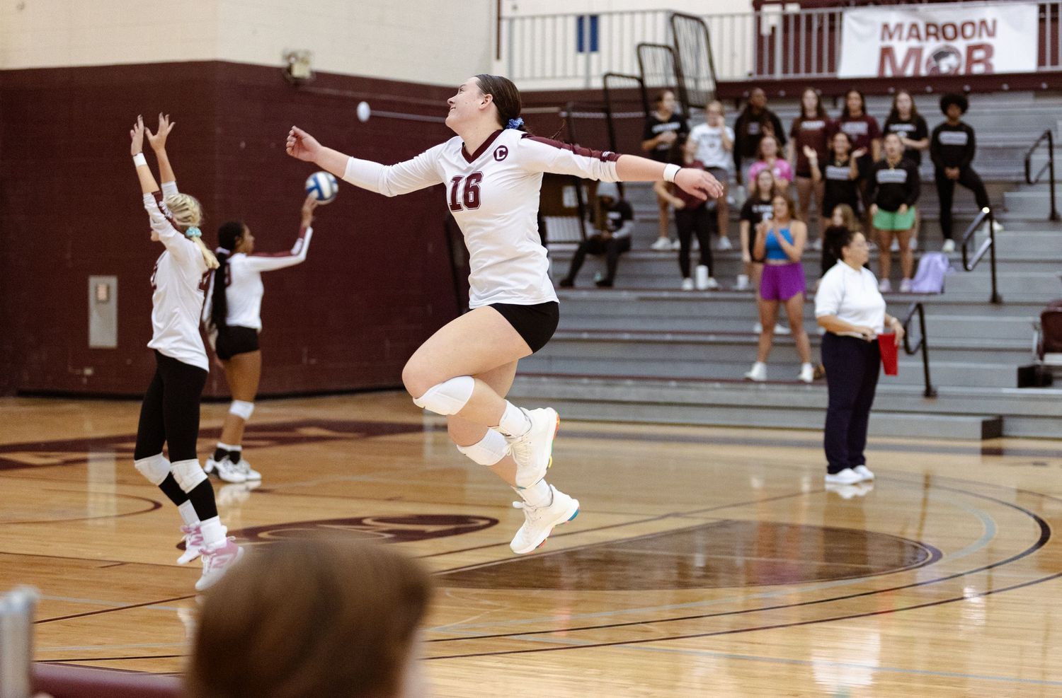 Volleyball player number 16 celebrates joyfully after scoring a point during a high school match.