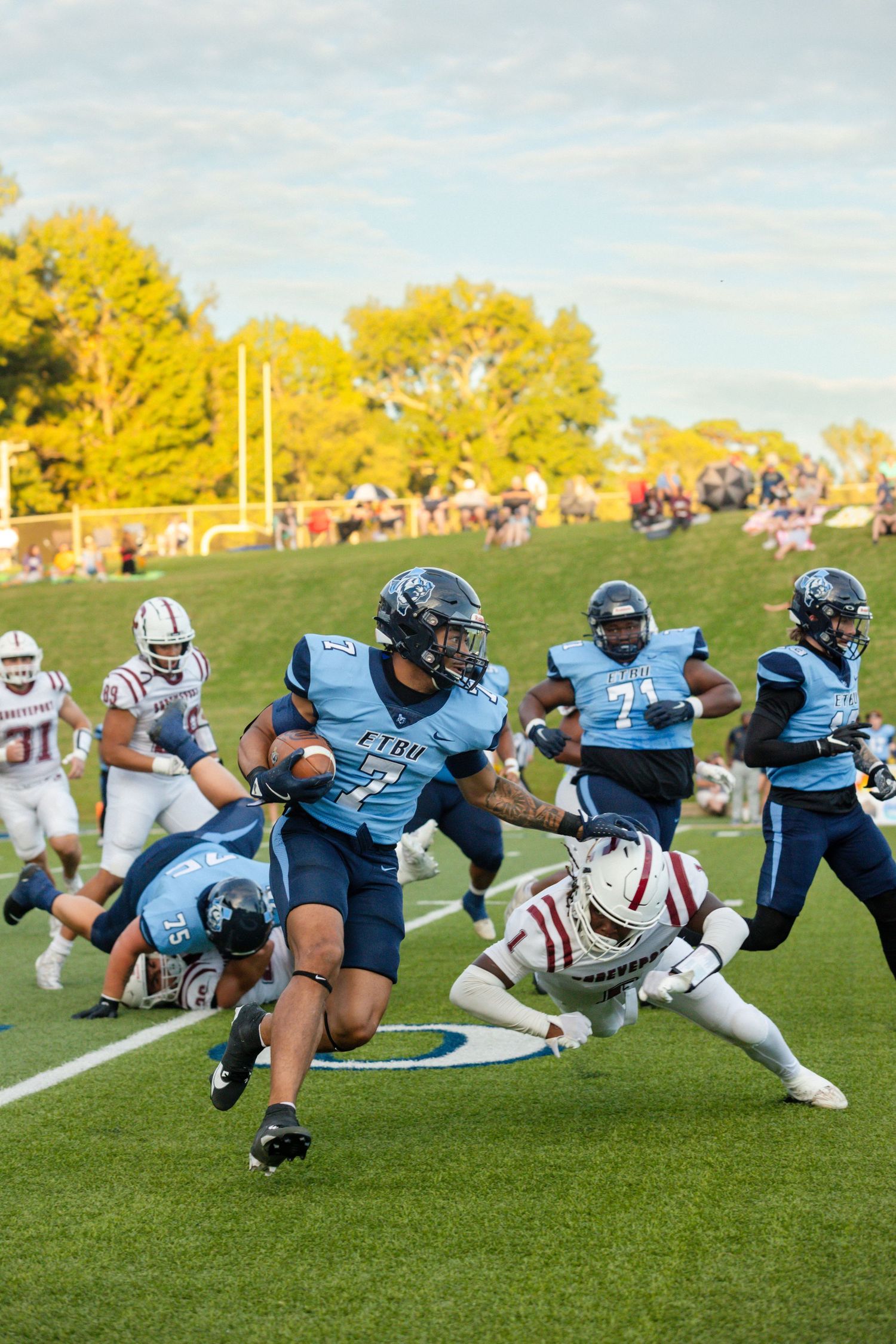 Blue jersey football player number 7 breaks tackle during outdoor college football game.