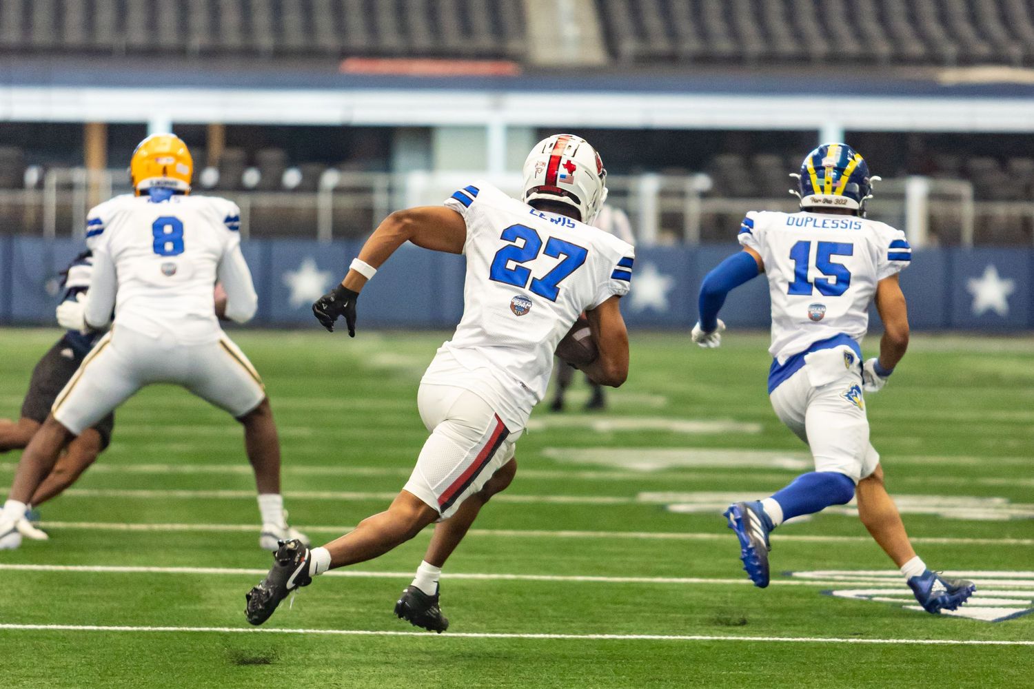 Football player number 27 runs with the ball during a youth football game in a professional stadium.