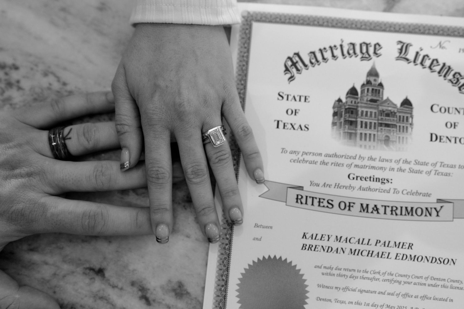 Hands with wedding rings resting on a Texas marriage license for Kaley Palmer and Brendan Edmondson.