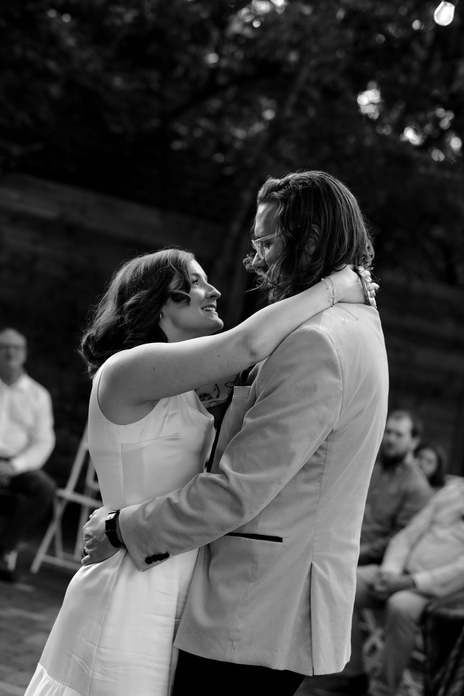 Bride and groom sharing their first dance at an outdoor wedding reception in black and white.
