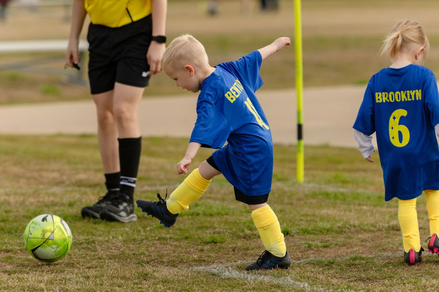 Young boy in blue jersey number 88 kicking soccer ball during youth league game.