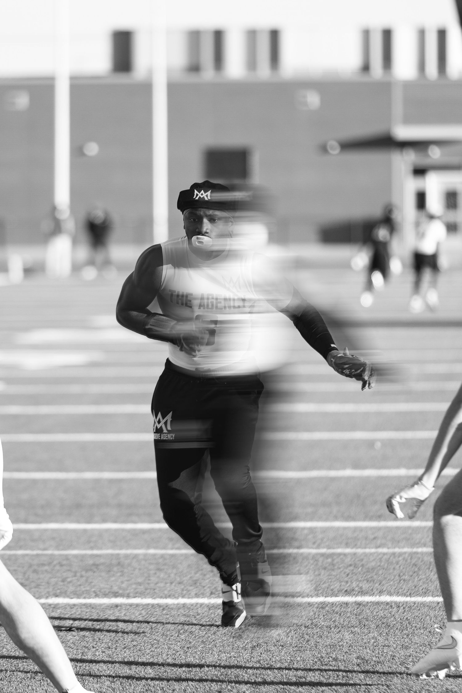 Black and white motion blur photo of athlete sprinting on a track field.
