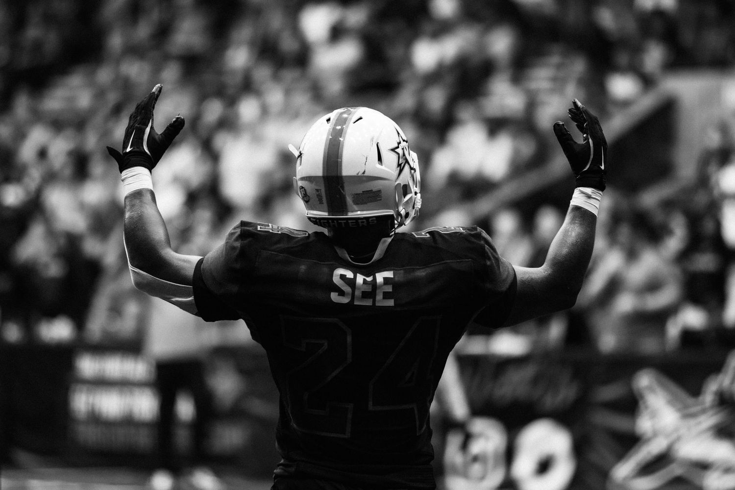 Black and white photo of football player number 24 SEE raising arms to crowd.