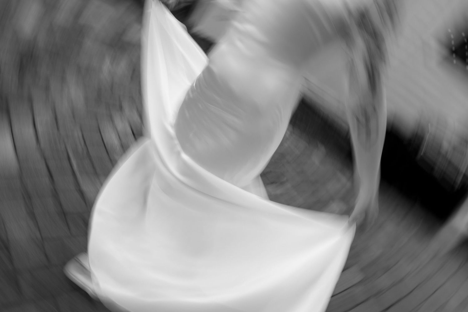 Blurred black and white artistic shot of a bride spinning in her wedding dress creating a dreamy motion effect.