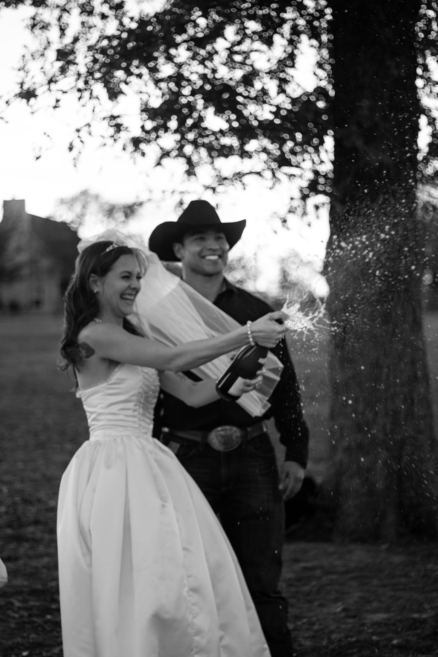 Bride and groom celebrating by popping champagne during their wedding portraits in a joyful documentary-style moment.
