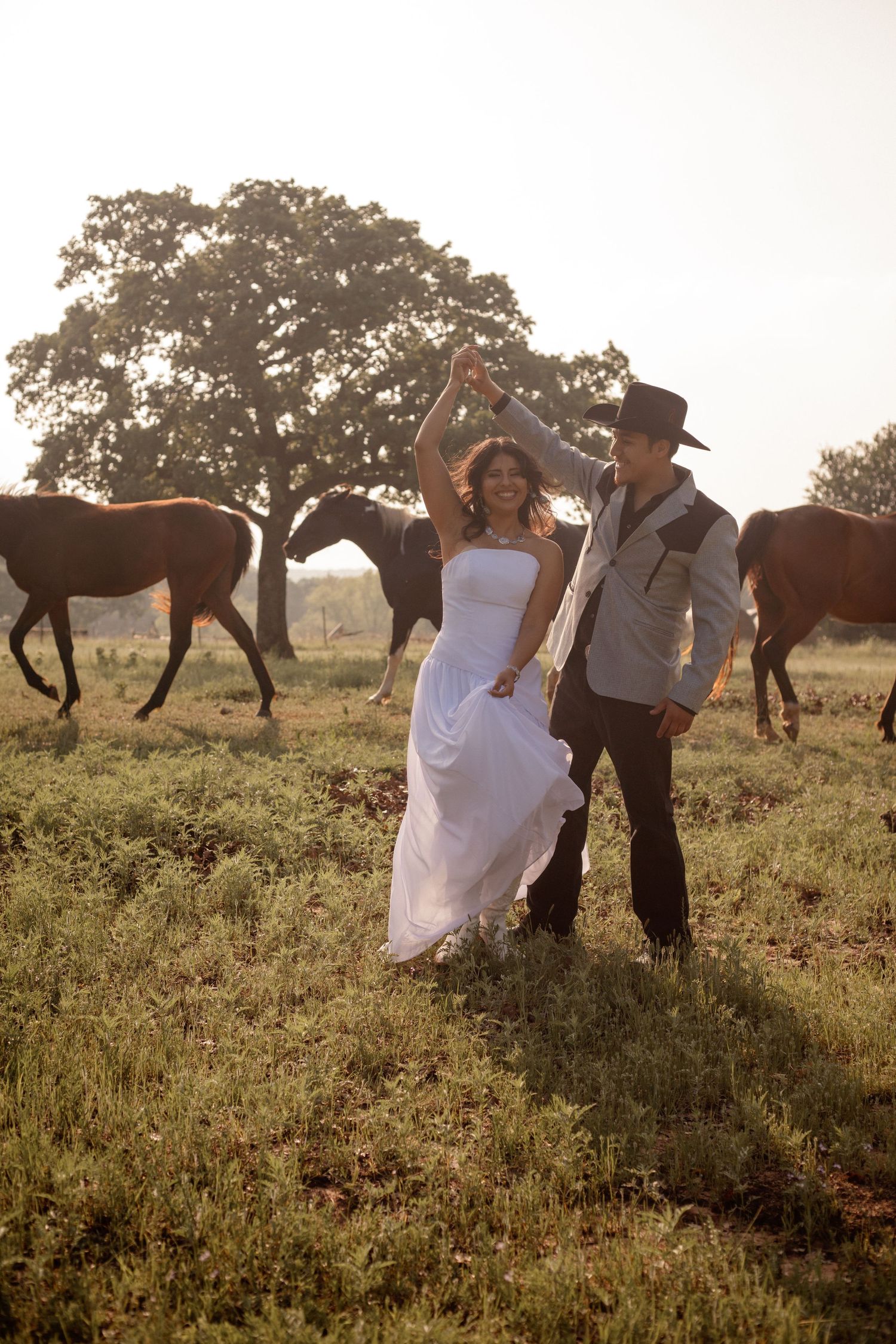 Bride twirling in her wedding dress surrounded by horses in a peaceful Texas field during romantic wedding portraits.