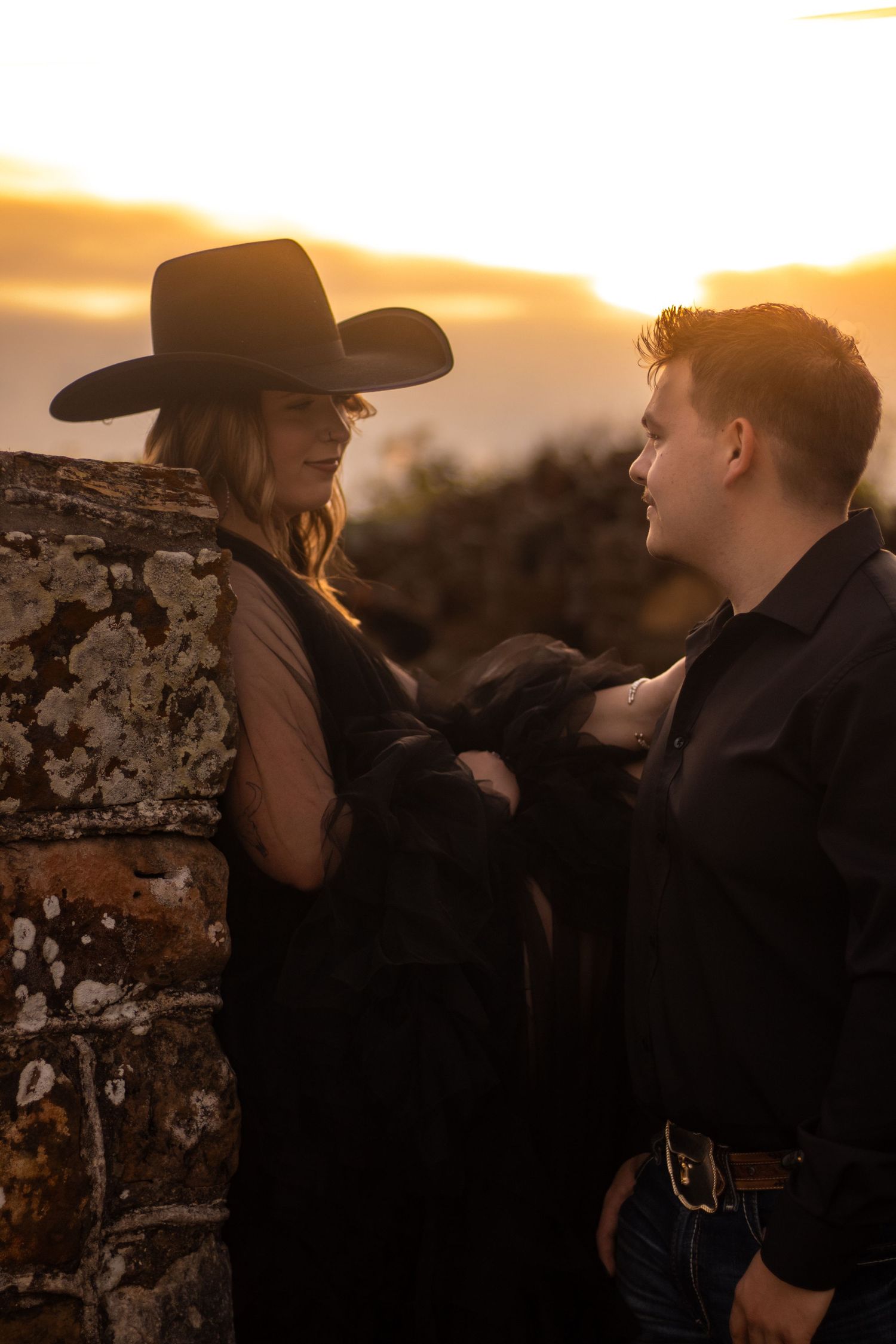 Couple embracing during golden hour engagement photos as the sun sets over the Texas landscape.