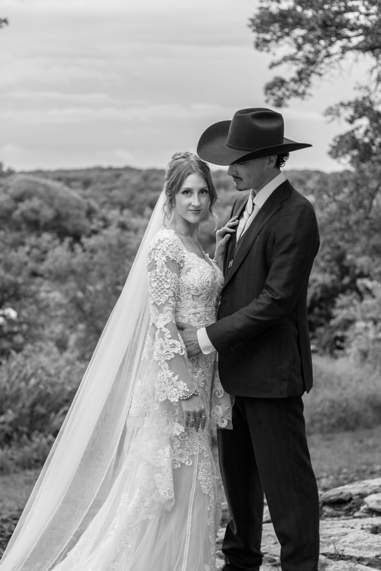 Black and white documentary wedding portrait of the newlyweds overlooking a breathtaking Texas cliffside landscape.