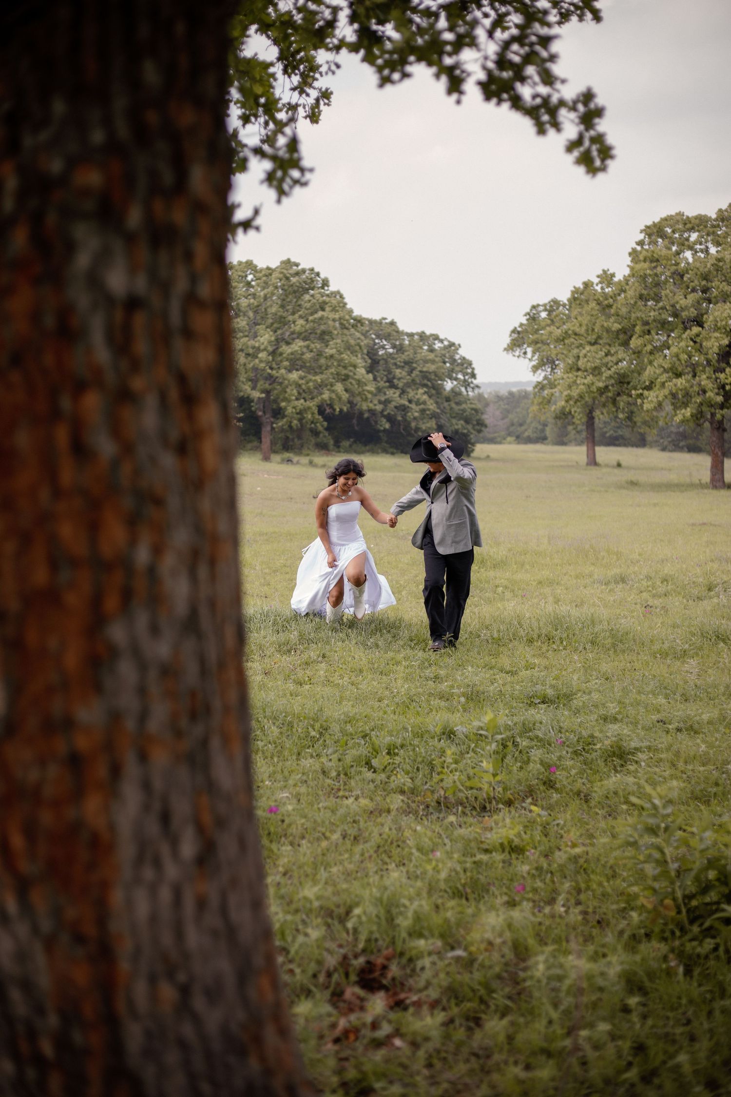 Bride and groom running hand in hand through a Texas wildflower field during their documentary-style wedding portraits.