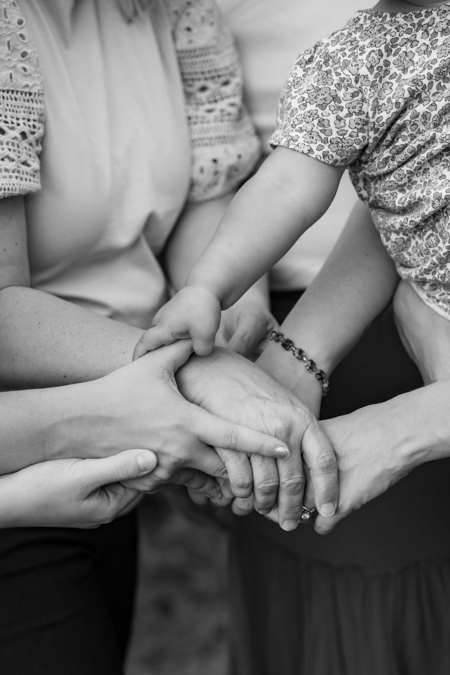 Black and white photo of multiple hands clasped together in unity, showing solidarity and support among a group of people.