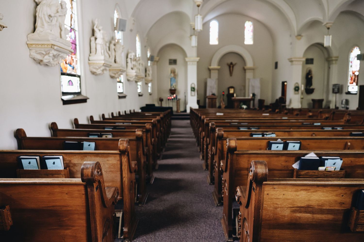 Empty church interior with wooden pews, arched ceilings, and tablets placed on benches for a modern worship service.