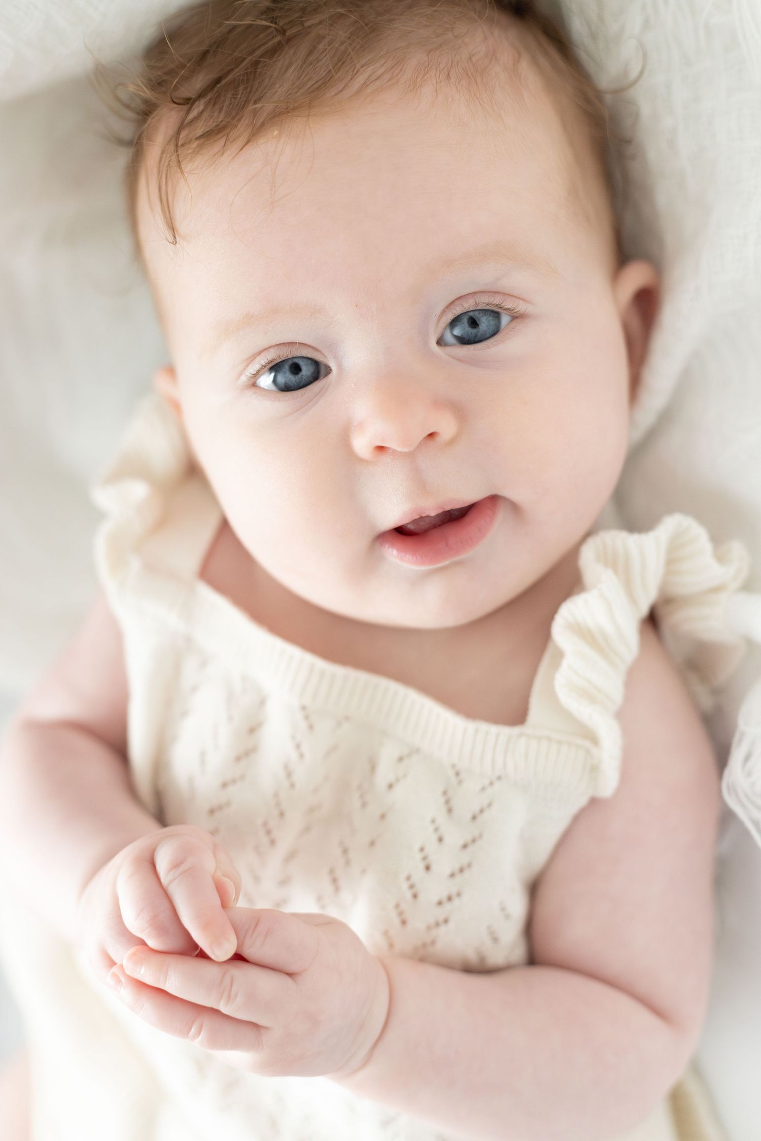 Blue-eyed newborn looking into camera wearing white clothes. | Bijou-Marie d'Image | Richmond VA Photography