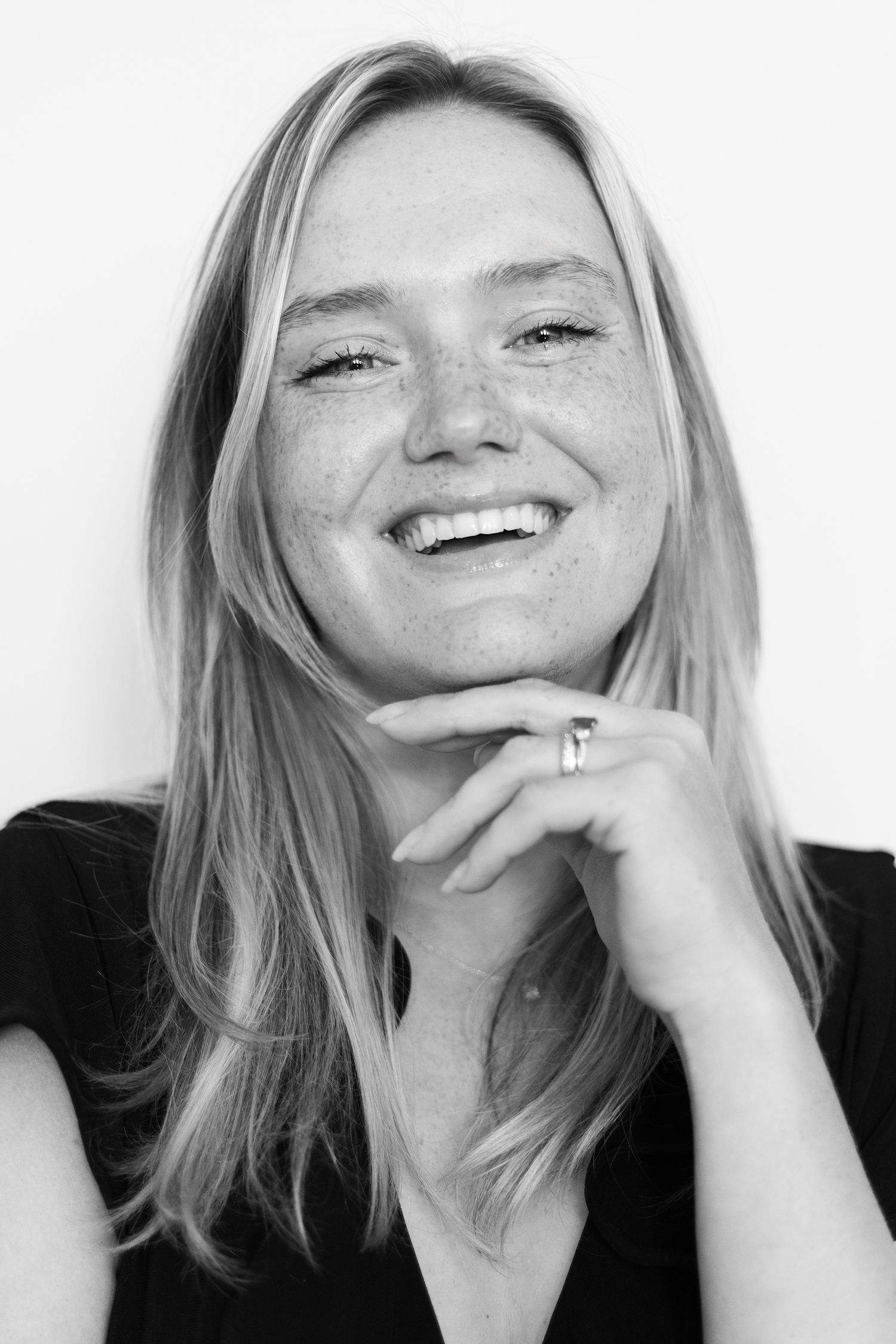 Black and white portrait of a woman with freckles smiling with her hand under her chin. | Bijou-Marie d'Image | Richmond VA Photography