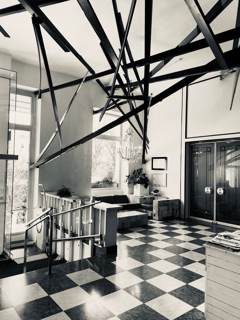 Black and white interior of a modern home with dramatic steel beams and checkered tile floor.