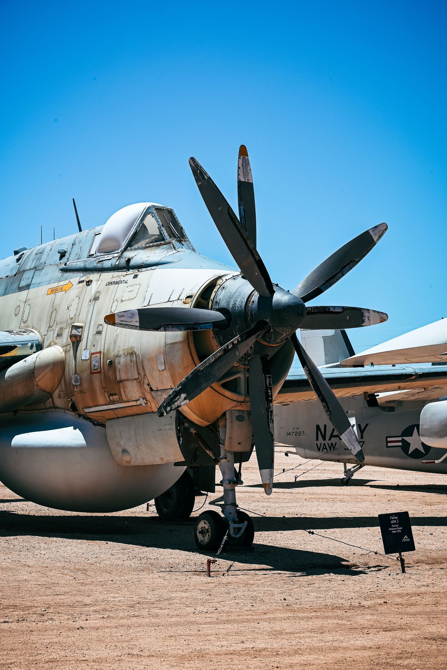 Close-up of a U.S. Navy propeller aircraft with weathered paint at an outdoor aviation museum.