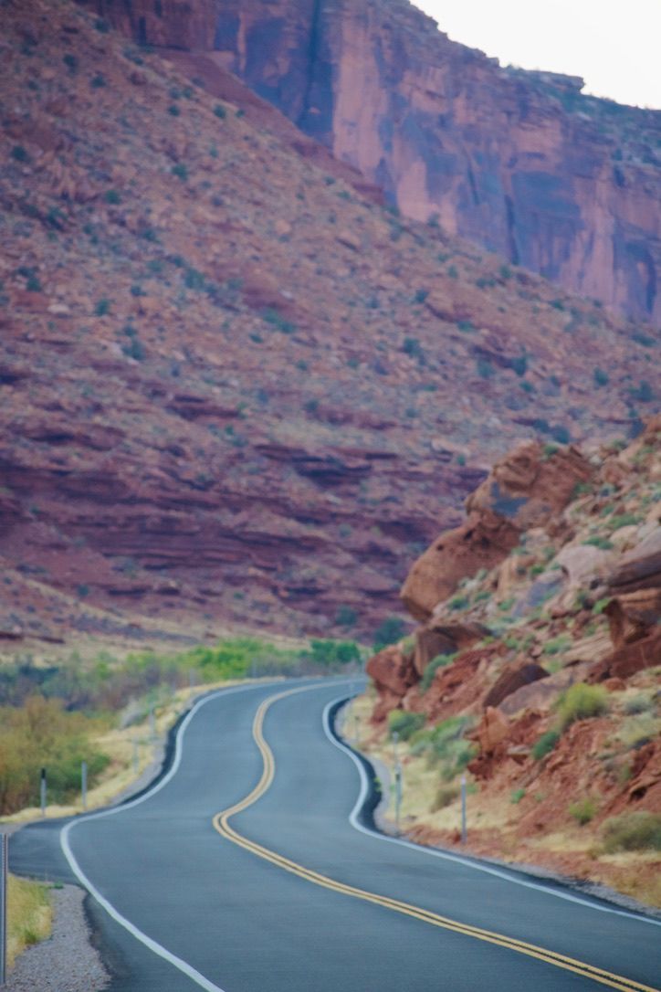 Winding two-lane road curving through dramatic red rock canyon walls in the American Southwest.