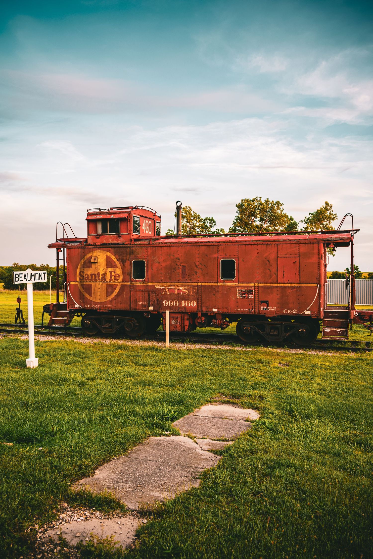 Weathered Santa Fe red caboose train car on display near a Beaumont station sign.