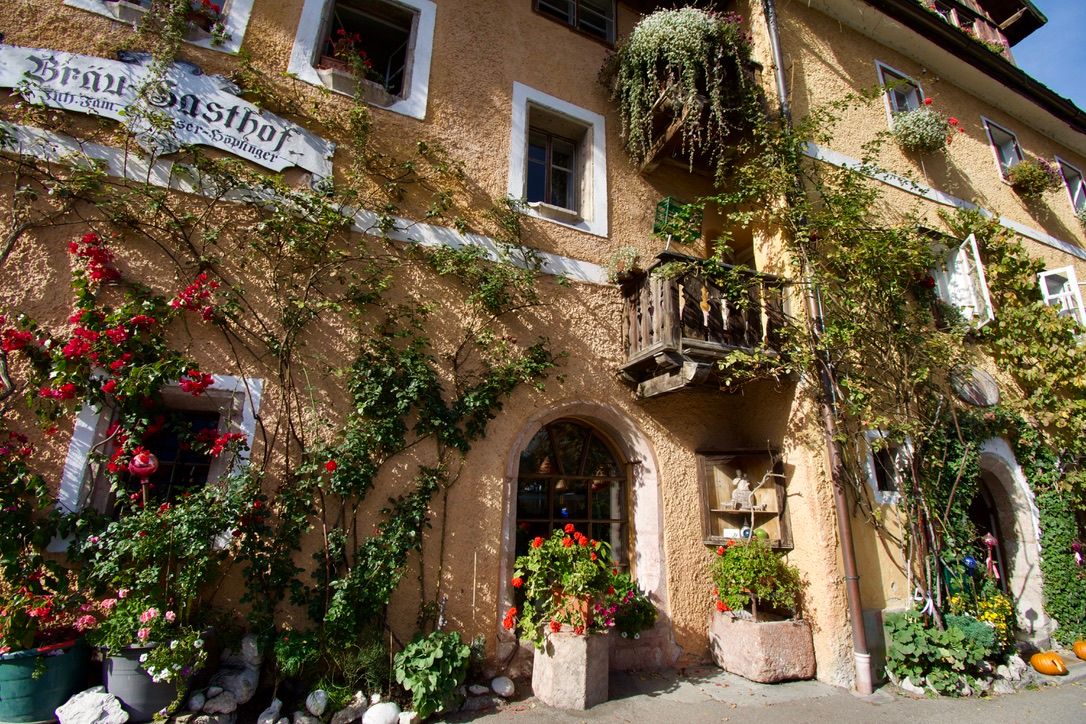 Charming European inn covered in lush climbing plants and colorful flowers with a decorative balcony.