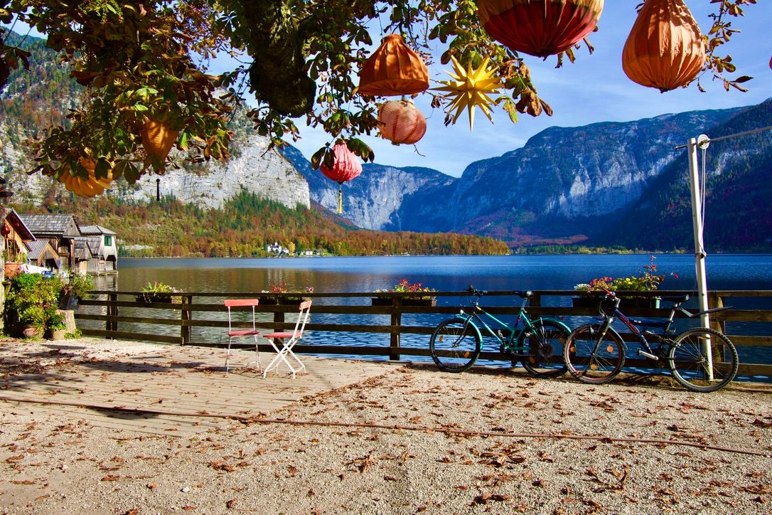 Bicycles parked by a scenic alpine lake with mountain views and colorful hanging lanterns in autumn.
