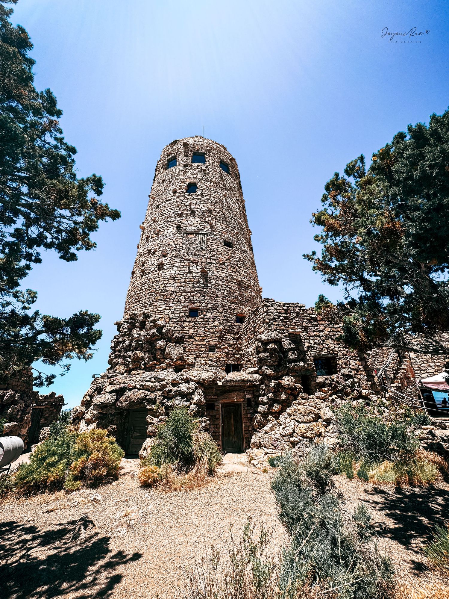 Historic Desert View Watchtower built of stone surrounded by pine trees at Grand Canyon, Arizona.