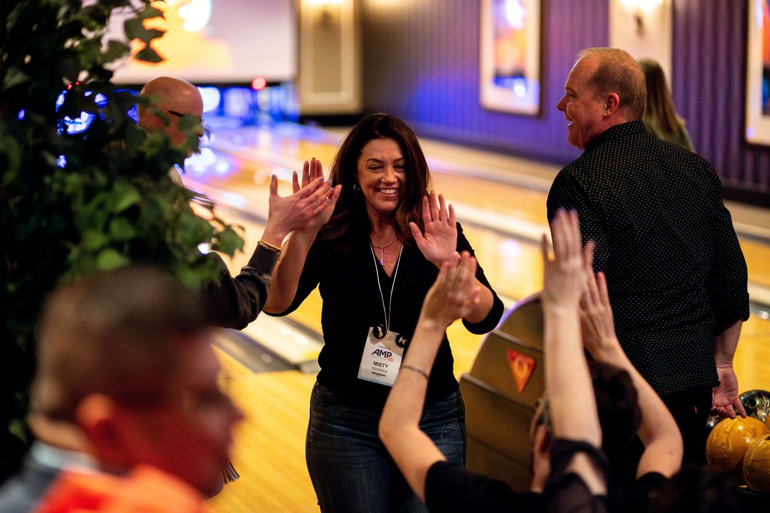 Woman giving high fives at a bowling alley event.
