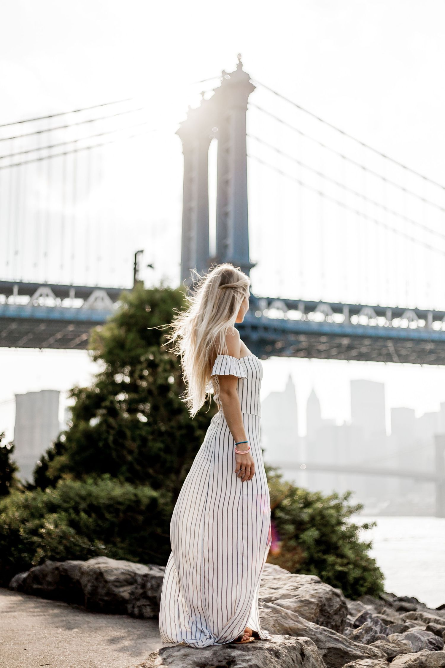 Candid portrait of a woman enjoying golden hour near the Brooklyn Bridge in New York City.