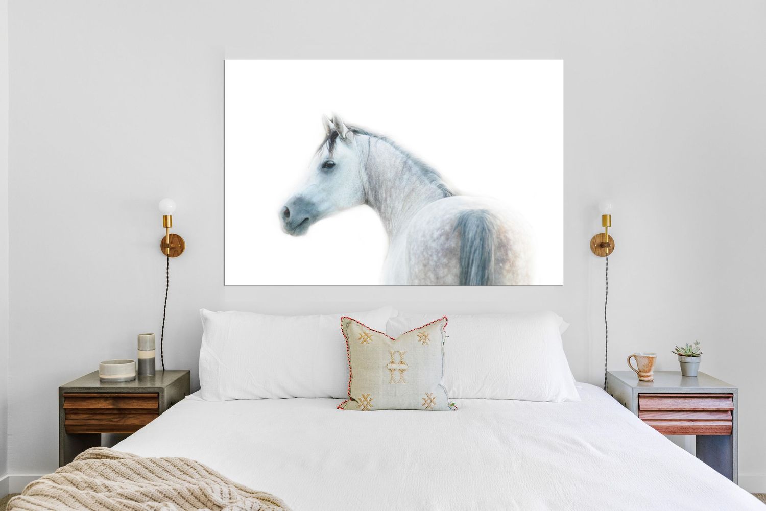 White horse portrait canvas wall art displayed above a bed with white pillows and gold sconce lighting in a modern bedroom.