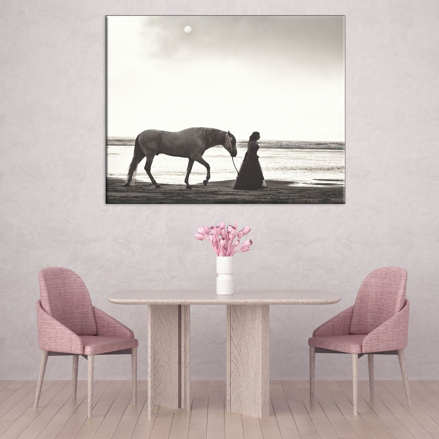 Black and white canvas art of a woman in a dress standing beside a horse on a beach, displayed above a table.