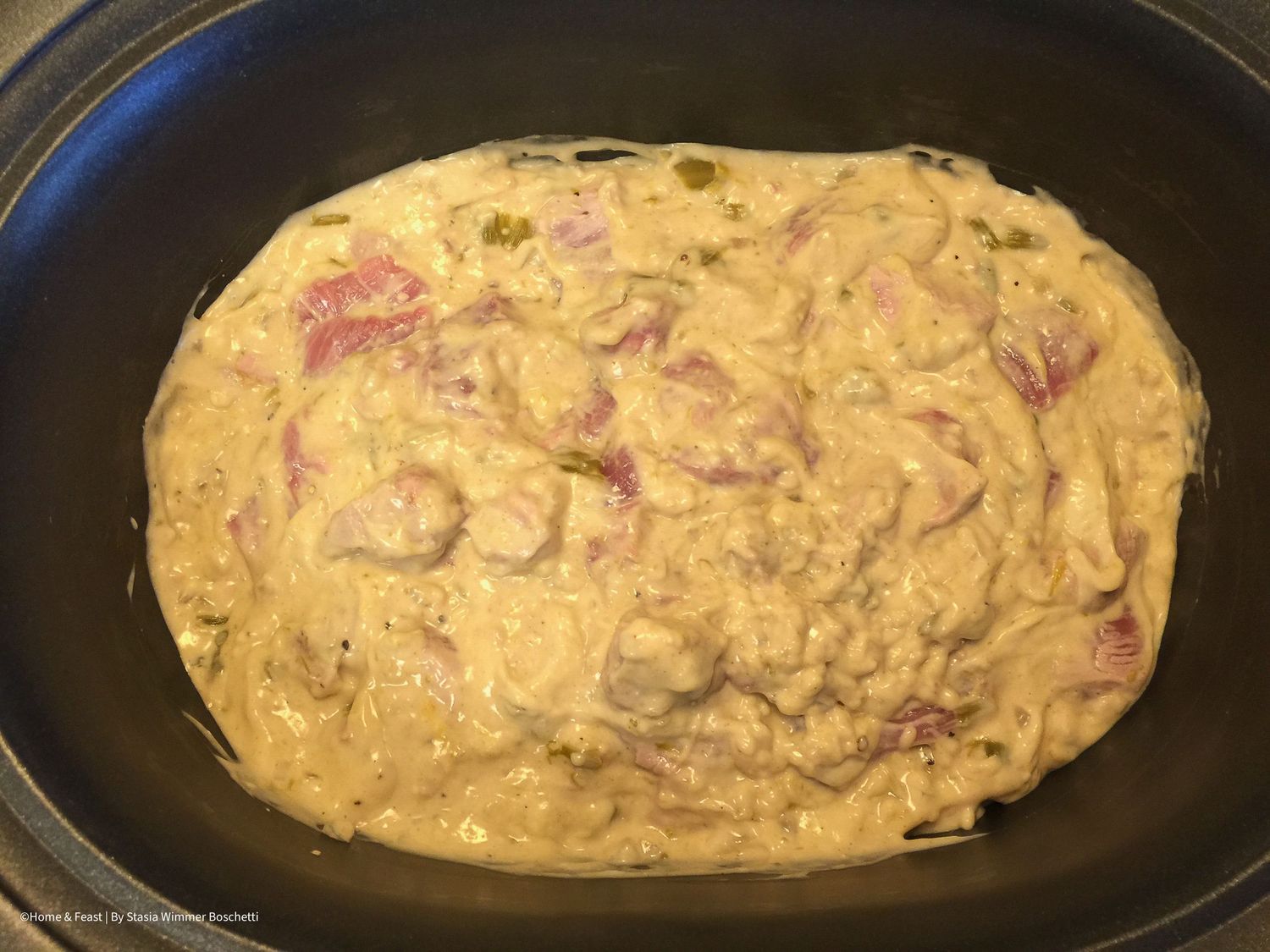 Cooked meat dish with creamy sauce browned on top in oval pan.