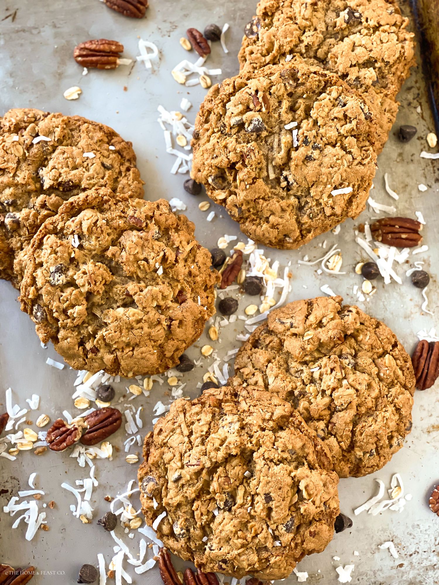 Overhead view of chunky oatmeal cookies with scattered pecans and coconut flakes.